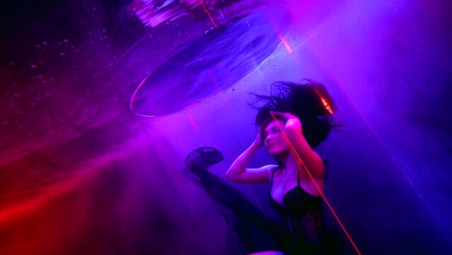 fascinating underwater shot with floating brunette woman in glass tube in pool deepness, slow motion