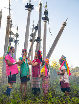 Various generation include young teen and old woman help to decorate and set hair and cloth of Long Neck Karen girl who stand in area of ceremonial courtyard of their village.
