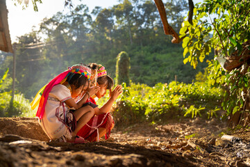 Two little Asian hill tribe children sit and pray to the right side to worship spirit or angel in...