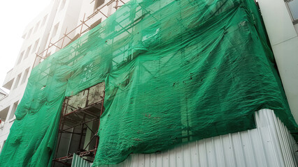Building under construction with scaffolding and safety green net installed to fall prevention...