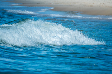 Small, pleasant waves crashing on the beach. Background with a sea wave on the theme of ecology and tourist weekend trips.