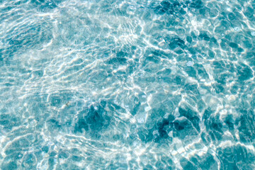 Fototapeta na wymiar Crystal clear water. Background of blue and clear sea water with bright highlights on the waves.