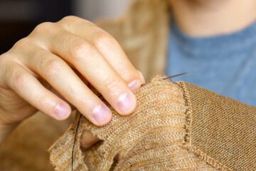 Hands men close-up. Mending clothes, sewing and darning, and fashionable needlework. Selective focus - obrazy, fototapety, plakaty