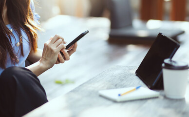 Asian freelance woman working and meeting on her smart phone on wooden table at outdoor cafe. Entrepreneur woman working for her new business concept.