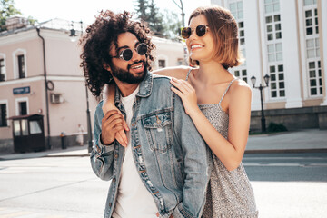 Smiling beautiful woman and her handsome boyfriend. Sexy cheerful family having tender moments in the street at sunset. Models hugging. Embracing each other. Love concept. In sunglasses