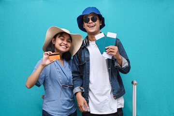Excited young tourist couple hold credit bank card and passport tickets