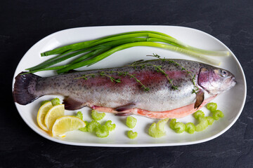 Fresh rainbow trout with fresh vegetables on white plate. Healthy lifestyle, mediterranean diet.