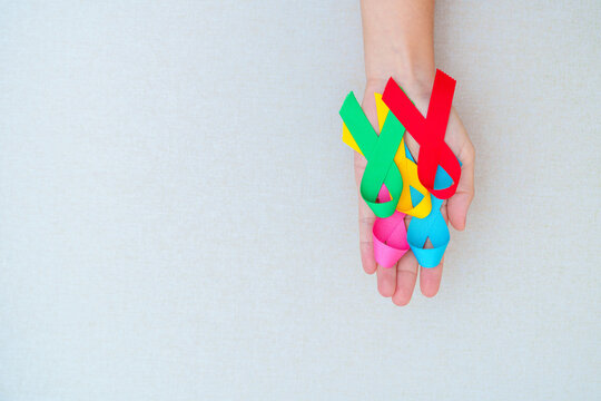 World cancer day, February 4. Hand holding blue, red, green, pink and yellow ribbons for supporting people living and illness. Healthcare and Autism awareness day concept