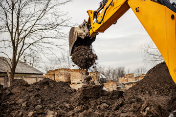 Cropped picture of an eartmover removing soil from on place to another on construction site.