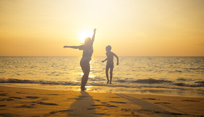 Mother and son jumping on the beach 