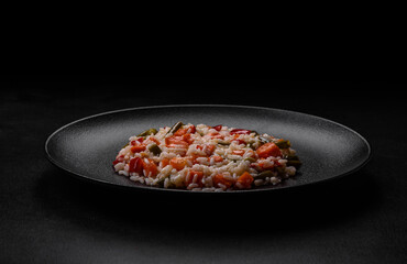 Delicious fresh risotto with vegetables, spices and herbs on a black plate