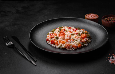 Delicious fresh risotto with vegetables, spices and herbs on a black plate