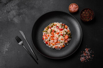 Delicious fresh risotto with vegetables, spices and herbs on a black plate