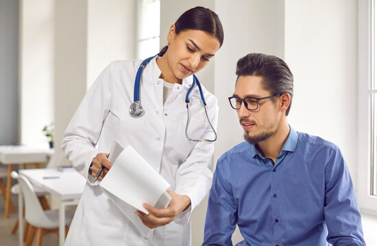Female doctor showing test results to male patient in medical clinic. General practitioner consulting male client at medical checkup visit in hospital. Medicine and healthcare concept