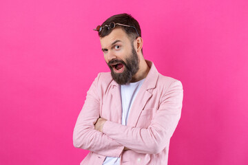 Bearded man dressed in a pink jacket with glasses. Emotional studio portrait.