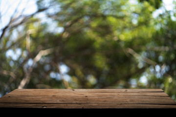 Empty wooden board on table top and blur inside abstract green background with natural bokeh, mock up for display of goods.