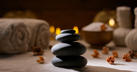 Fototapeta na wymiar Beautiful composition of various spa bodycare supplements. Close up shot of massage hot stones with bath salt, towels and candles on background 