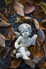 Icy angel statuette surrounded by leaves in winter