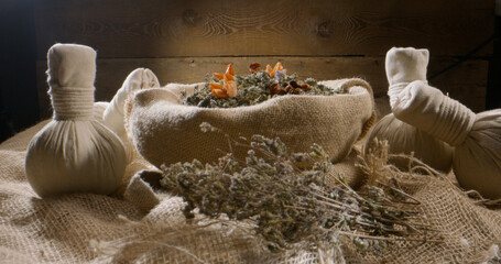 Dry aromatic leaves in flowers in jute sack. Medical plants for bodycare or alternative medicine. Composition with spa herb balls for massage 