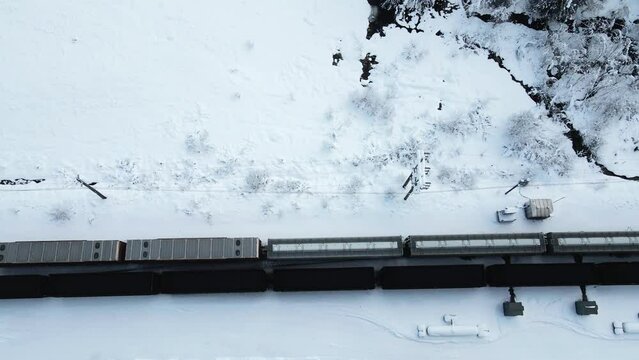 Cargo Trains Pass Each Other in Snowy Landscape from a Bird's Eye View