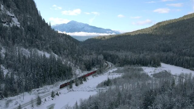 Freight Train Journey Through Snowy Forests and Majestic Mountains in British Columbia, Near Revelstoke in the wintertime