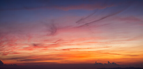 A vibrant sunset or sunrise sky panorama with cloudscape in soft magenta, pink and orange tones as a background or texture
