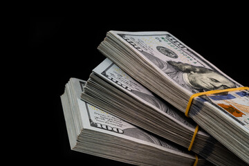 Three bundles of 100 american dollar bills on a black background