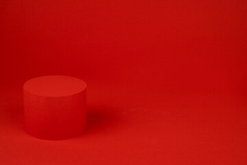 Red cylinder podium mockup on table on rich saturated background for presentation cosmetic products, gifts, goods in elegant minimal modern style, copy space. Template for advertising, design.