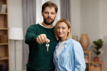 Obraz premium Happy Couple Holding Key. Happy Young Family Holding Key To New Home On Moving Day. Real Estate Owners Embrace Proud Buying Property