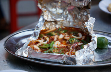 Squid cooked with spicy sauce in aluminium foil paper served on the street of Kuala Lumpur         ...