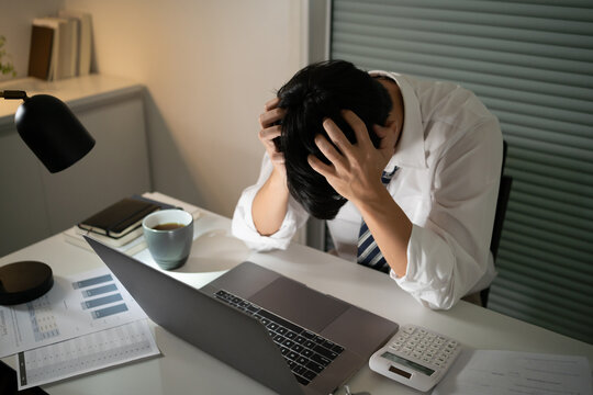 Tired Asian Business Man Falling Asleep At Table Alone Working Late At Night.on Laptop Computer At Night In Dark Office. Works In The Later Time