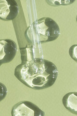 Drops of serum or hyaluronic acid gel with a pipette on a green background. Smears of cosmetic skin...