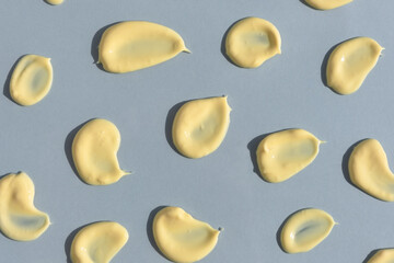 Yellow cream texture on a gray background. Smears of skin care cosmetics product. Wellness and beauty concept. Top view.