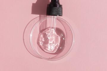 Hyaluronic acid serum or gel for the face with a pipette in Petri dish on a pink background. Concept of cosmetics laboratory researches, wellness and beauty.