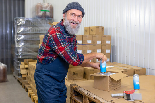 Cheerful man packing canned drinks for shipping