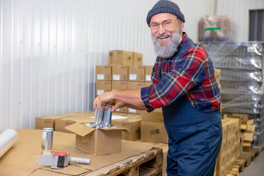 Joyful man packing canned beverages in the factory