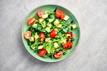 Salad with avocado and cherry tomatoes in the kitchen, cooking process in the kitchen