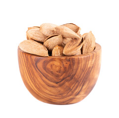 Mountain almonds in wooden bowl, isolated on white background. Uzbek wild almonds.