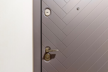 Chrome handle with keyhole on white door with panels in frames. Entrance. Close-up photo of architecture detail
