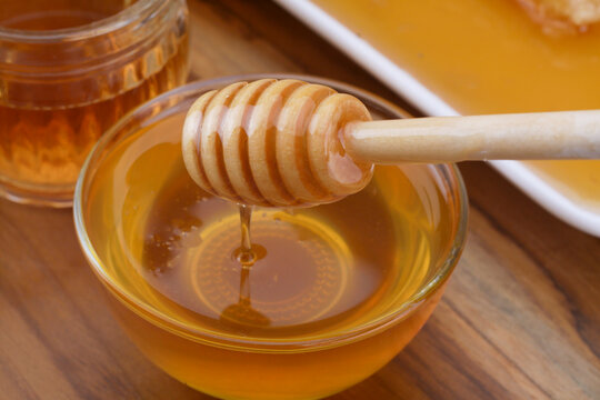 selective focus Honey dripping from honey dipper in a bowl. Close-up.