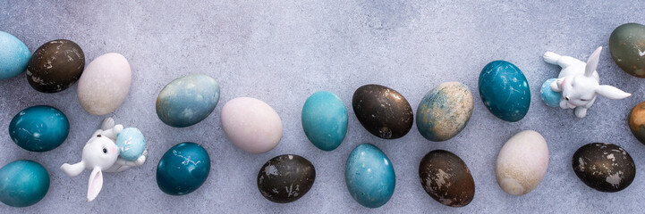 Colorful Easter eggs and cute bunnies on a pastel pink background, top view, copy space, Easter banner