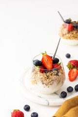 Homemade granola with almonds in a glass with yogurt, fresh strawberries and blueberries, delicious healthy breakfast