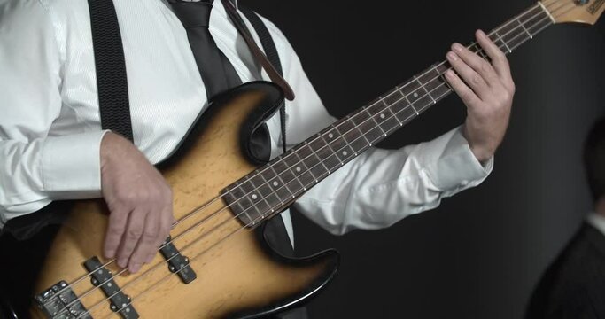 Close up footage of a man playing bass guitar in the studio, music concert, 4k
