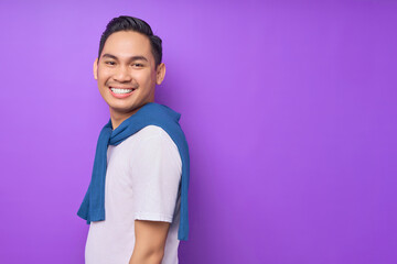 Smiling young Asian man wearing white t-shirt is standing and looking at camera isolated over purple background. people lifestyle concept