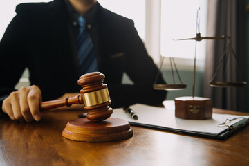 Business and lawyers discussing contract papers with brass scale on desk in office. Law, legal services, advice, justice and law concept picture with film grain effect