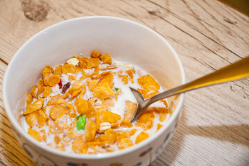 Healthy cereal - corn flakes in a white bowl on wooden background.