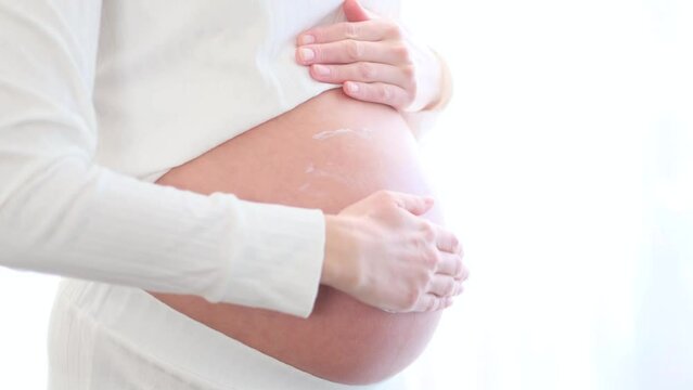 A beautiful pregnant woman touches her belly.