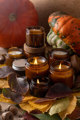 Soy candles burn in glass jars. Tree leaves, pumpkin. Comfort at home. Candle in a brown jar. Scent and light. Scented handmade candle. Aroma therapy. Autumn mood. Cozy home decor in fall.