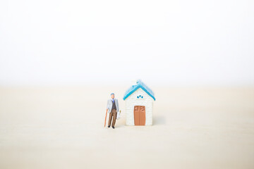 Fototapeta na wymiar Miniature old man holding grocery bag with miniature house with space on blurred background, retirement home, elderly care service concept