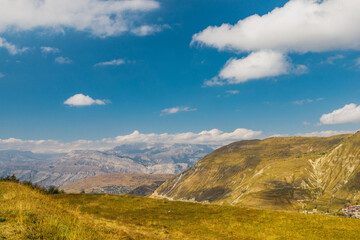 Snow-capped mountains and autumn fields. Beautiful mountain landscape in winter. Panoramic view, Dagestan, Russia.